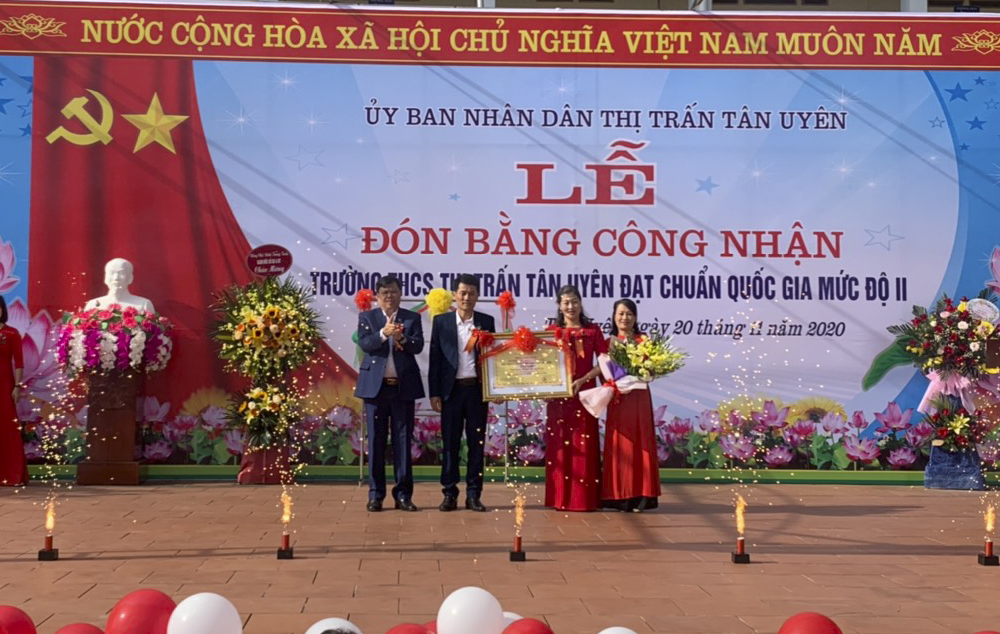 Đại diện lãnh đạo Huyện ủy, UBND thị trấn tặng hoa và trao Bằng công nhận đạt chuẩn quốc gia mức độ II cho Trường THCS thị trấn Tân Uyên.