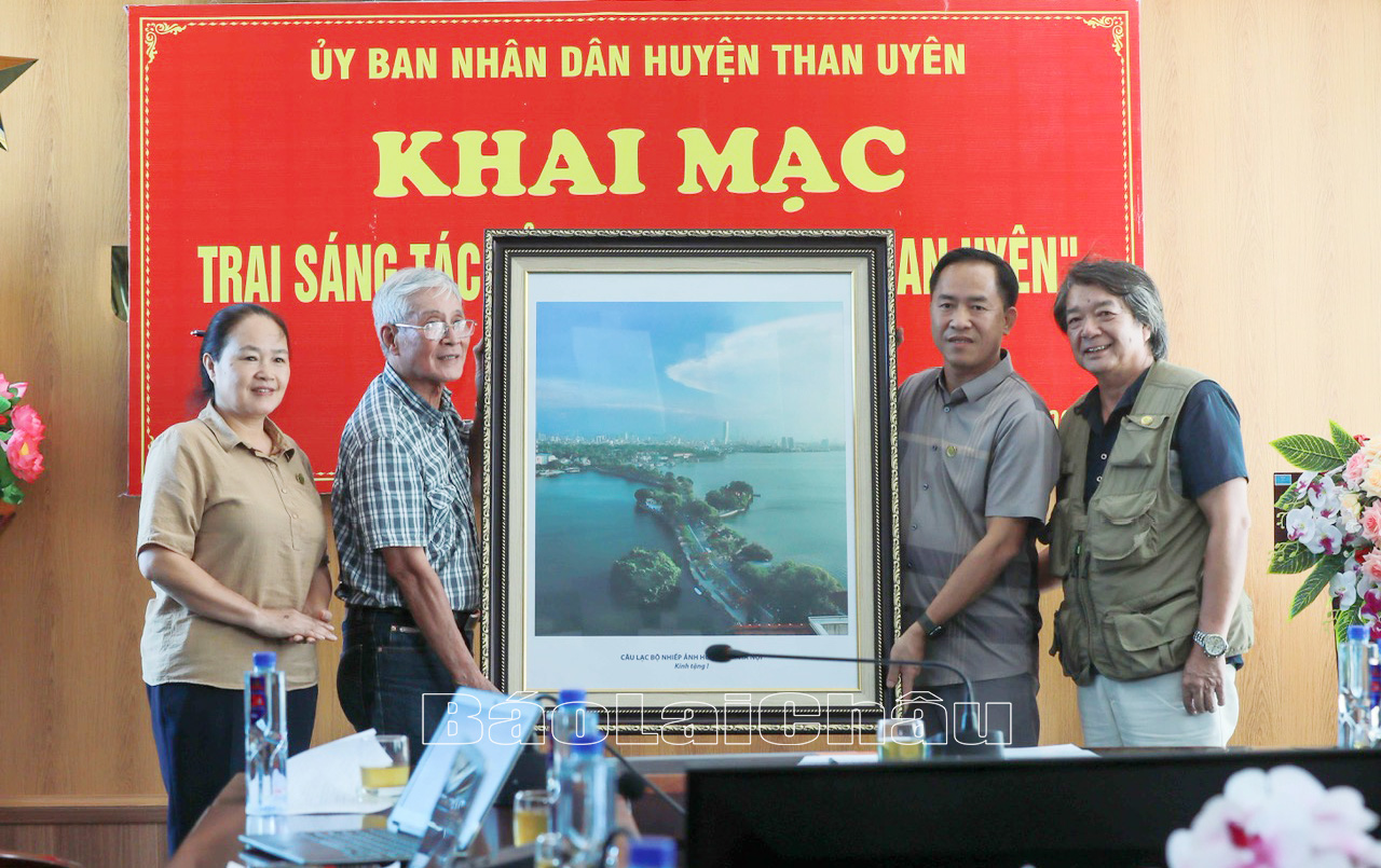 Đại diện Câu lạc bộ Nhiếp ảnh Hồ Gươm (Thành phố Hà Nội) tặng lãnh đạo huyện Than Uyên bức tranh mang tên “Đường Thanh niên Hồ Tây”. 